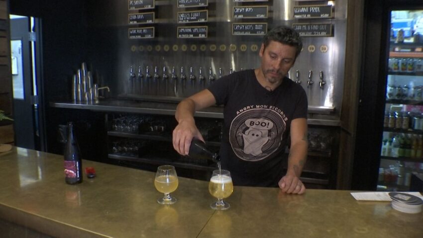 bartender and brewer at prison city brewing pouring sour ale made with rhubarb into a glass