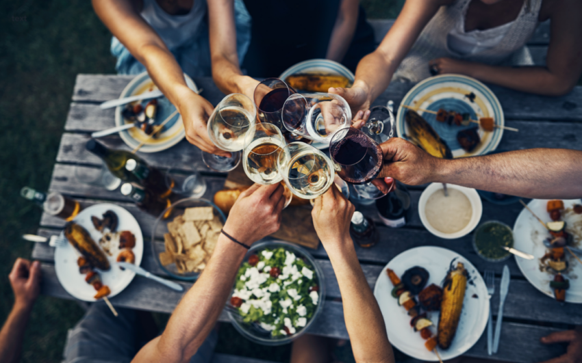 table of food with people holding wine