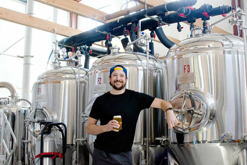 Levi Liberty enjoys one of his beers in front of Social Fabric Brewery’s three fermentors in Port Townsend. (Elijah Sussman/Peninsula Daily News)