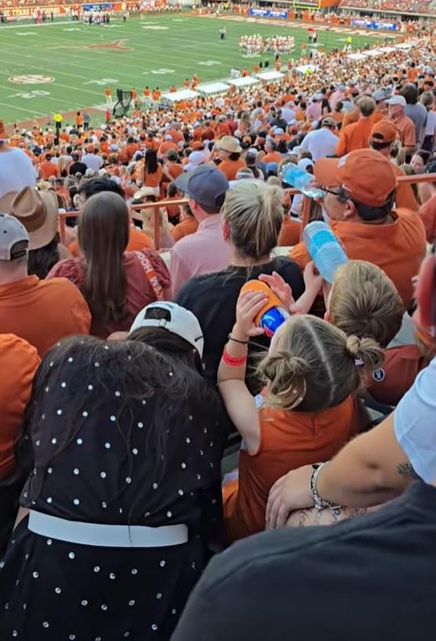 Seorang balita perempuan terlihat minum bir selama pertandingan sepak bola Texas di Austin pada hari Sabtu